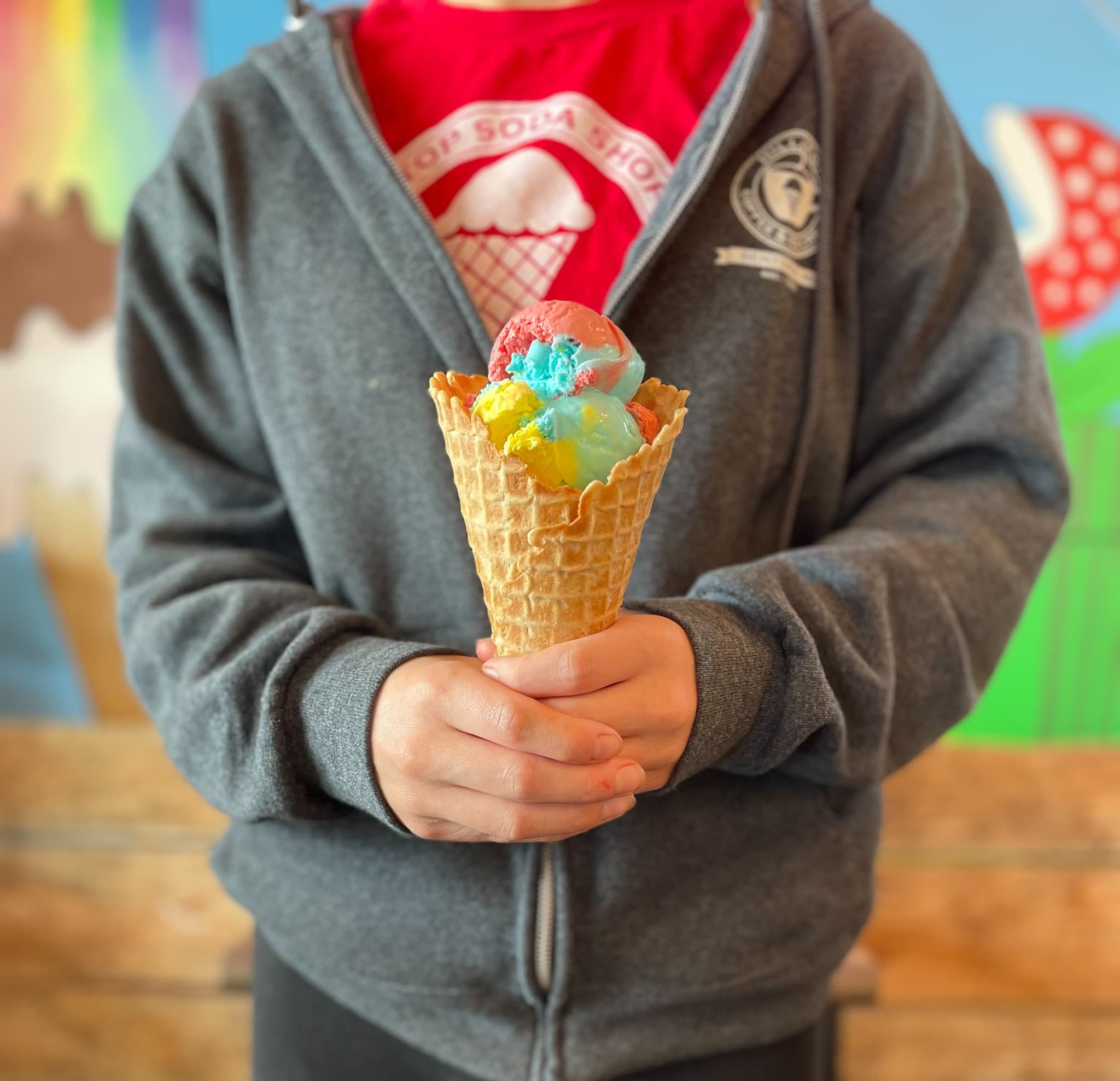 A colorful ice cream cone held in two hands